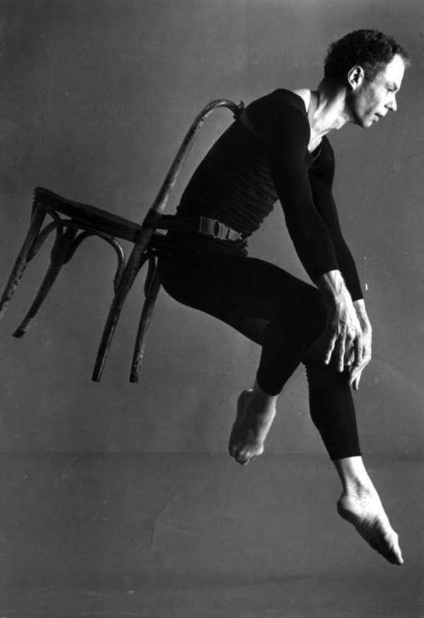 Merce Cunningham with a chair on his back 
