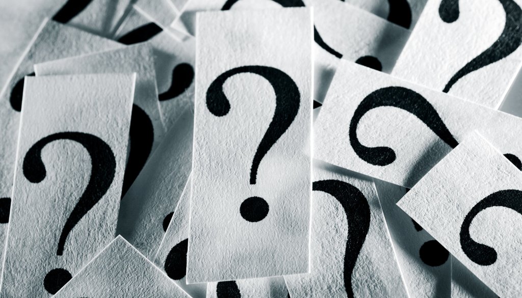 A pile of typed question marks on textured white paper.