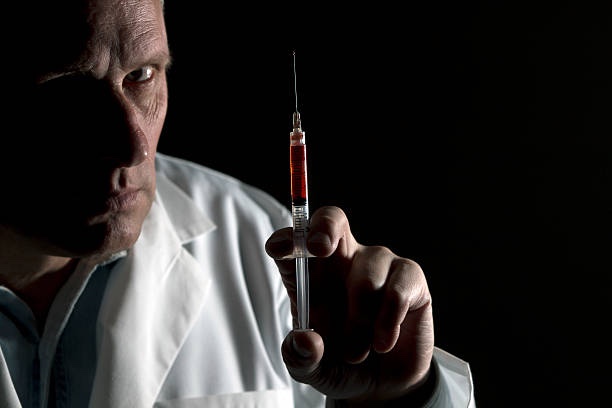 Evil doctor  with blood filled syringe 